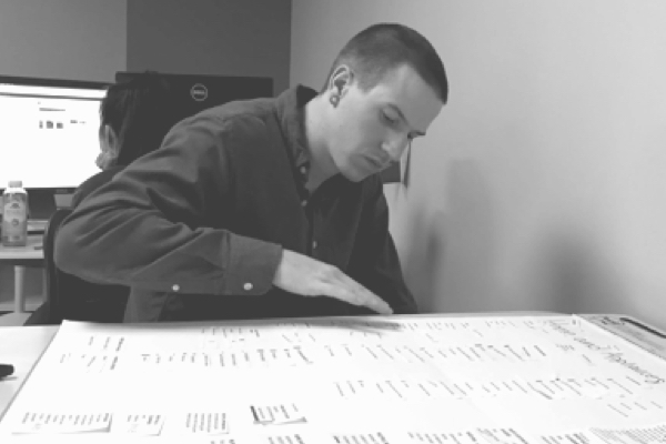 Young man organizing clips of paper on a pad of paper