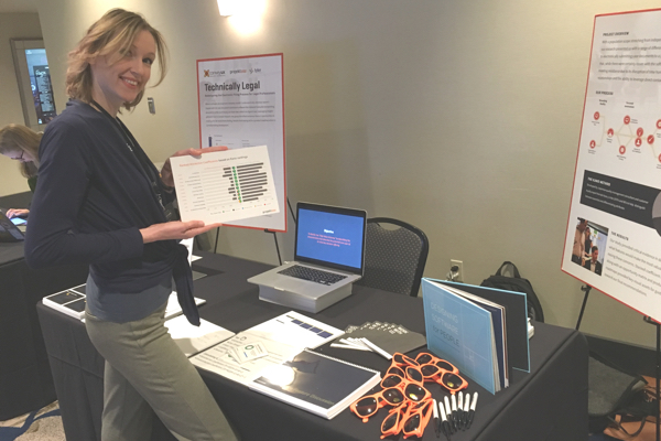 Woman standing at a table surrounded by presentation material and company swag